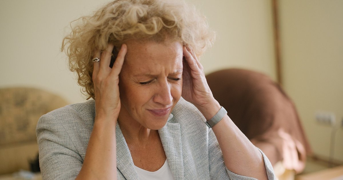 Woman pressing both hands to her temples, illustrating headache warning signs